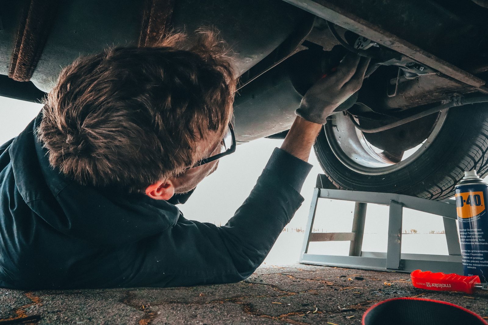 Technician working under a car during a roadside repair